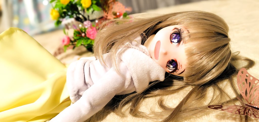 少女のドールが横たわりこちらを見て微笑んでいる