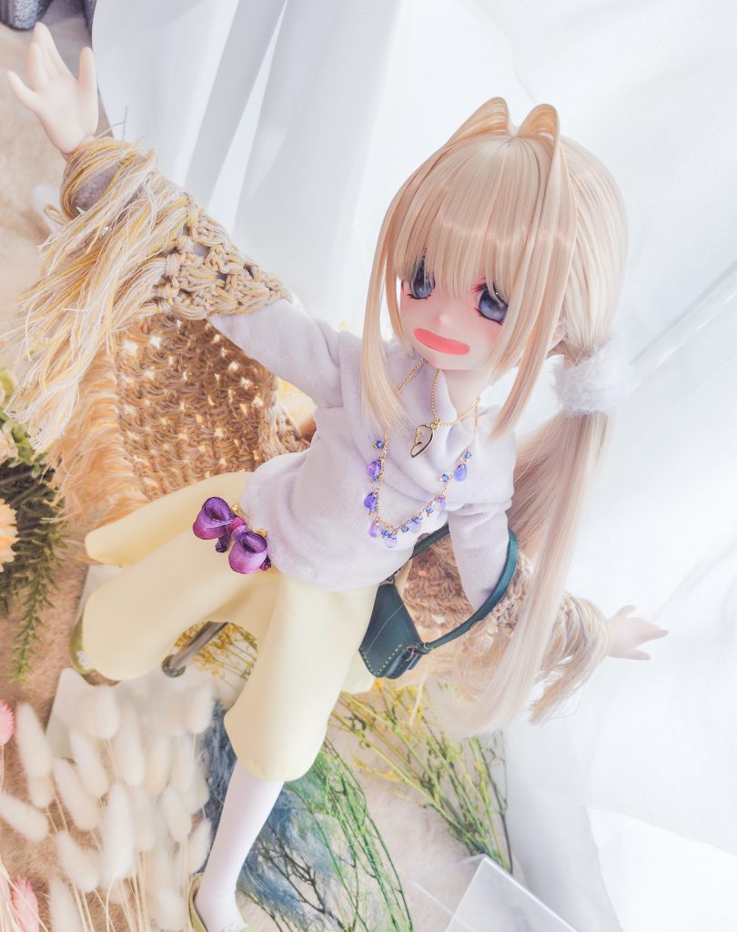 少女のドールが薄茶色のショールをかけた両腕を広げている